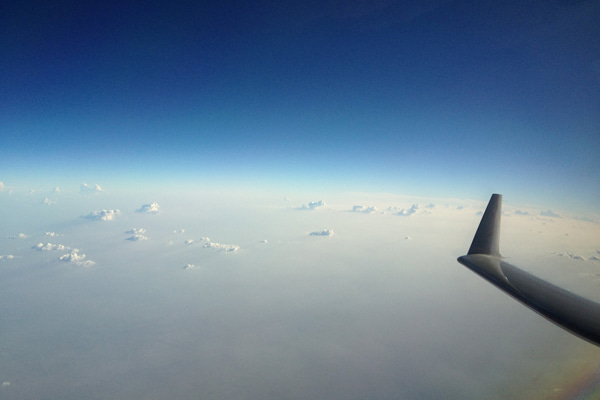 Aerial view from an airplane window featuring a blue sky