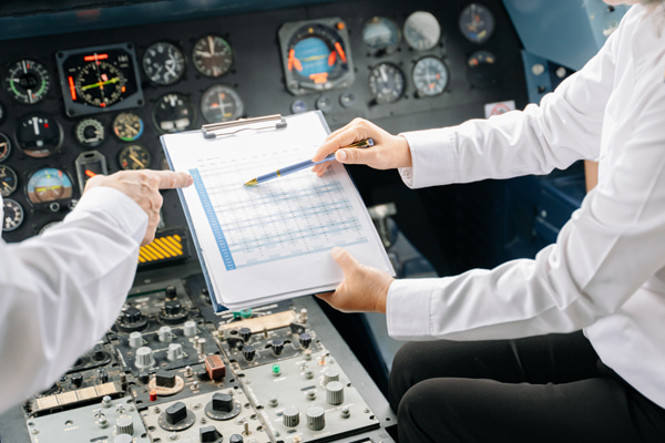 Two individuals in an aircraft cockpit reviewing a document