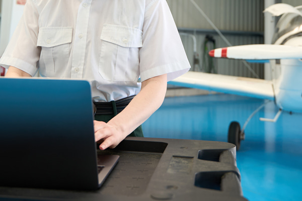 Person in a pilot uniform working on a laptop