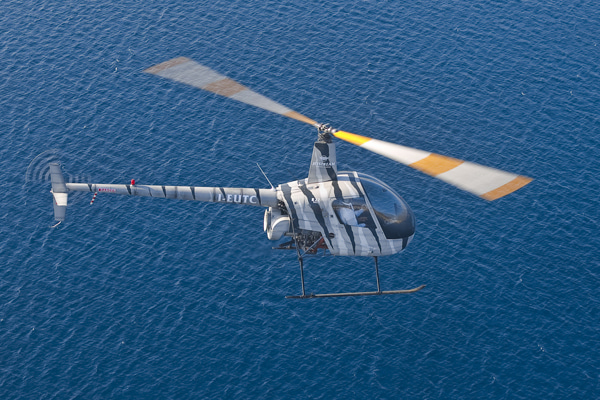 Two-seat helicopter flying over the open sea