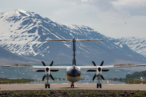 Passenger aircraft on a runway with snow mountains in the background