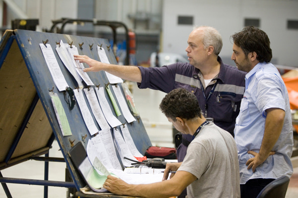 Three people reviewing documents and checklists