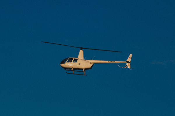 Helicopter Robinson R44 flying against a clear blue sky