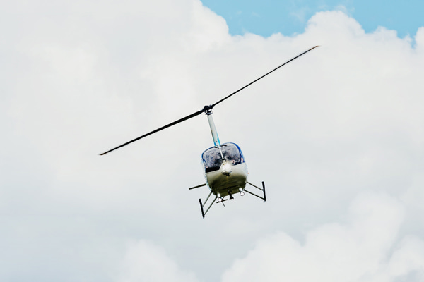 Helicopter Robinson R66 flying against a cloudy sky